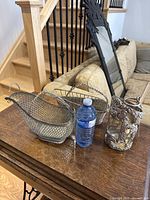 Photo showing all three silver plate wire baskets and ornate holder on wooden table for size reference including a water bottle