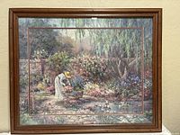 Framed lithograph artwork by Barbara Mock showing a woman gardening in a colorful floral garden by a pond with ducks.