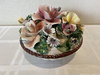 Front angle showing hand-painted porcelain flowers in pastel colors and textured base.
