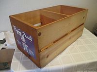 Wooden crate with natural finish, divided interior, and Piggy Pears label on side showing cartoon pig in clothes.