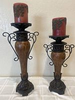 Two decorative candle holders placed side by side showing height difference and details of metal and ceramic design topped by decorative red candles