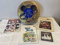 Photo showing the Disney Trivia Game tin, three vintage books/magazines with Mickey Mouse on the cover, and a 101 Dalmatians CD case.