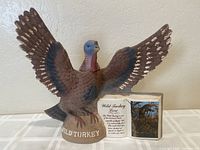 Front view of ceramic decanter showing wild turkey with wings spread, labeled 'Wild Turkey' and the lore label next to it