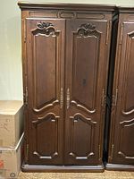 Front view of antique style pine armoire with closed double doors and carved decorative panels.
