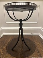 Full front view of the black metal accent table showing tabletop and base
