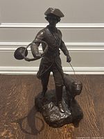 Front view of entire bronze statue showing hunter holding horn and dog
