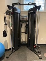 Front view of Inspire home gym showing dual cable pulley towers, weight stacks and chin-up bar