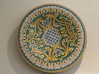 Front view of large round intricately decorated Italian ceramic platter charger with floral and baroque motifs.