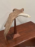 Full side view of antler eagle sculpture on wood stand
