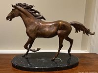 Full side view of bronze stallion sculpture on oval marble base