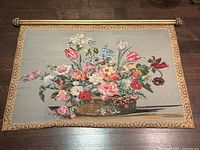 Full view of the floral tapestry mounted on the gilt wood hanging bar showing the entire piece and floral design.