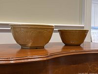 Front view of both yellow ceramic mixing bowls showing textured pattern and grip stands.