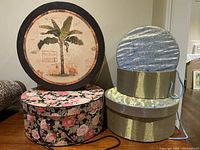 Five vintage style hat boxes stacked and arranged showing variety of sizes and designs.