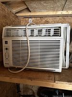 Full view of Danby window air conditioner sitting on wood surface showing front vents and power cord.