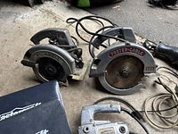 Photo showing Rockwell Skil circular saw and Porter-Cable circular saw with cords on concrete floor