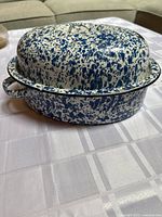 Side view of old primitive enamel roaster showing blue speckled design and offset handle.