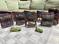 Lot display showing nine Disney Pixar Cars figurines in original packaging with two loose figurines placed in front.