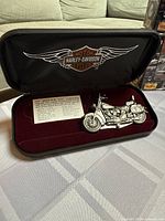Silver Harley Davidson motorcycle model in black display case with Harley Davidson logo and informational card.