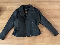 Black leather motorcycle jacket laid flat showing front with braided leather side detailing, zippered pockets, and snap collar.