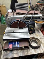 Mastercraft Belt and Disc Sander showing sanding belts on and included loose on wooden surface.