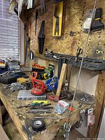 Workbench with hammers, drill bits, clamps, measuring tools, and small hardware on a wooden surface.