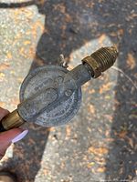 Close-up of the propane regulator showing metal construction and connection fittings, with markings about installation directions.