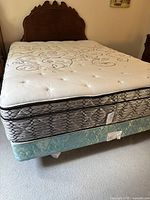 Full view of queen bed with mattress and vintage style wooden headboard visible, showing decorative carved top.