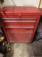 Front view of the red metal toolbox with visible 3 drawers and one cabinet door at the bottom.