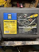 Closed black plastic carrying case with Power Fist label showing kit contents and specifications: 120V, 8000 to 30000 RPM, 40-piece accessory set, flexible shaft, adjustable stand.