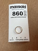 Photo of the ring on a white label showing lot number and general notes for auction identification.