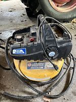 Front angle view of the yellow Campbell Hausfeld air compressor with black motor housing showing brand and model stickers.