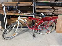 Full side view of the Supercycle men's cruiser bicycle, showing red and white frame, rear rack, and black padded seat