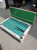 Multiple angled photos of the children's multi-game table showing the pool table surface with cues and balls and the foldable top panel in upright position.
