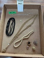 All costume jewelry and silver necklace items arranged in box; includes brooches and necklaces as described.
