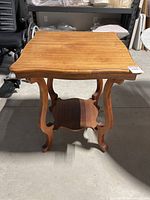 Front view of the mahogany fern table showing the square top, curved legs, scalloped lower shelf, and visible wood grain.