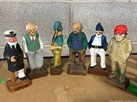 Group photo of 6 carved wooden figures including Cape Cod figure and Tom Hannah signed pieces showing front view