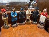 Group view of six wooden carved figurines by Tom Hannah