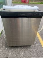 Full front view of stainless steel dishwasher with packaging on top