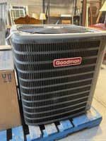 Front view of Goodman outdoor condenser unit showing logo and grille