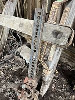 View of the jack post showing the wooden support and the perforated vertical metal bar with holes for the lifting mechanism.