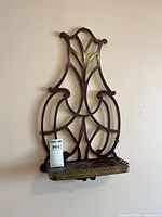 Front view of ornate wooden knickknack shelf with brass-edged shelf in wood cutout frame design.