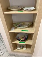 Five assorted handpainted plates displayed on shelf including two labeled Limoges plates.