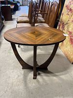 Front view of oval table showing wood veneer top with chevron pattern and curved wooden legs.