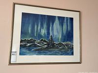 Front view of framed watercolour painting showing northern lights over a rocky landscape and water with a silhouetted tree in the center.