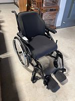 Three-quarter view of assembled wheelchair showing frame, seat, back and wheels