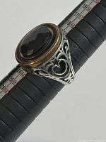 Front top view of the ornate silver men's ring with faceted brown stone showing detailed filigree work and gold-toned bezel edge.