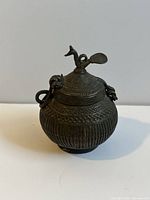 Full view of the antique cast iron box showing detailed ribbed and patterned decoration and the bird-shaped handle lid.