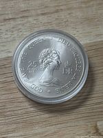 Silver Jubilee Medal showing Queen Elizabeth II profile from front side, clear plastic protective holder.