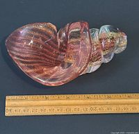 Side view of the aventurine art glass snail figurine with ruler showing length about 6 inches.