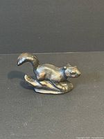 Front angled view of the vintage cast iron squirrel figurine showing detailed sculpted features and curled tail.